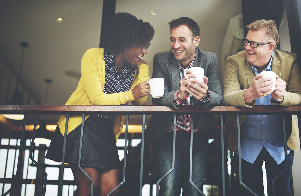 woman and two men smiling holding coffee cups while socialising