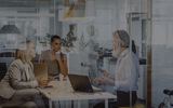 Modern glass office with two women and a man talking in a meeting